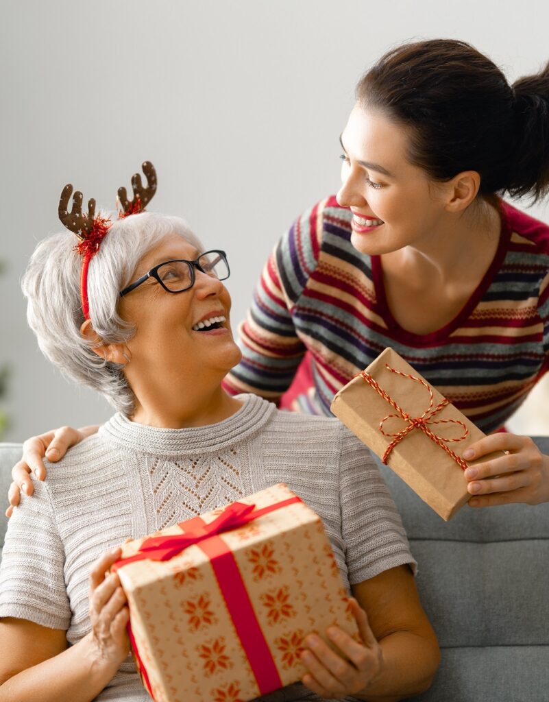 Volunteer Woman Giving Gifts To A Senior | Heritage Waterside Moving To A Senior Living Community | Bahama Bay Club